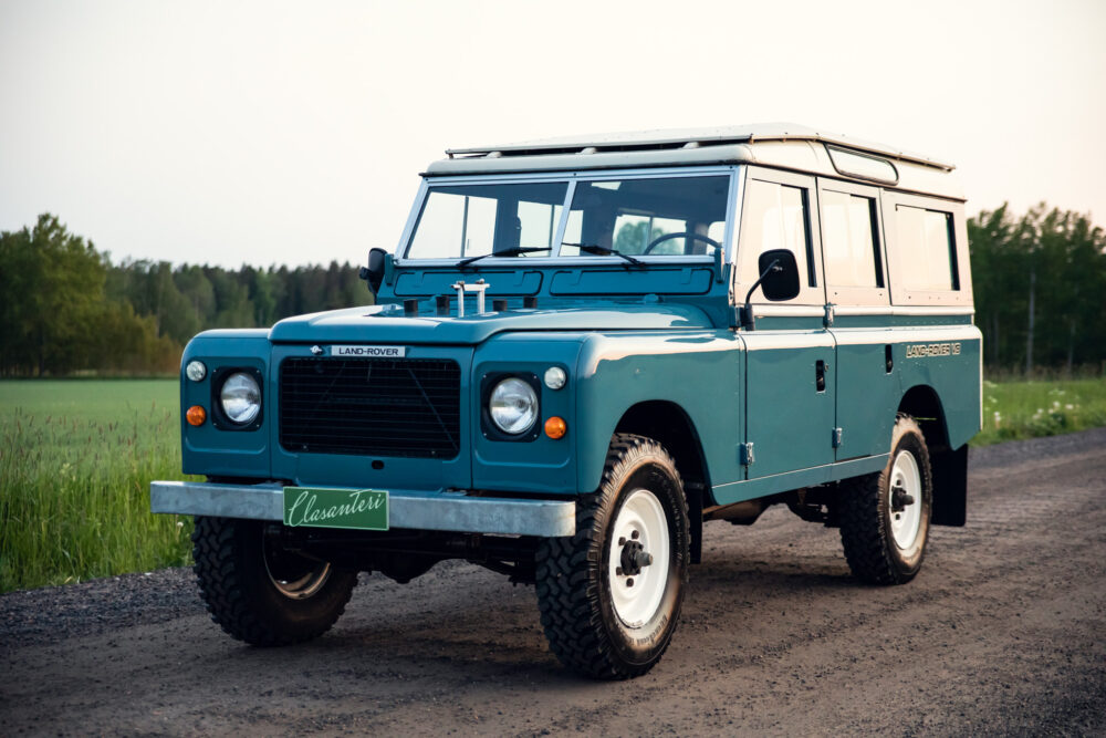 Vintage blue Land Rover on rural road at dusk