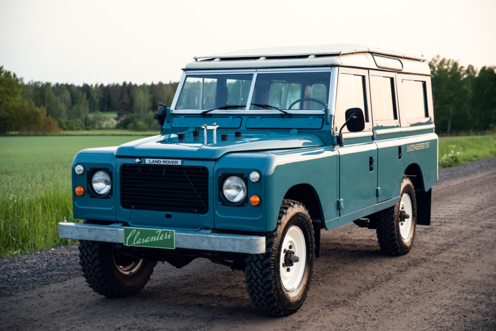 Vintage blue Land Rover on rural road at dusk