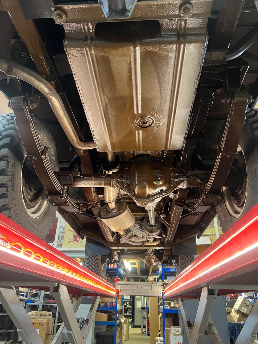 Undercarriage view of a vehicle in a repair shop.