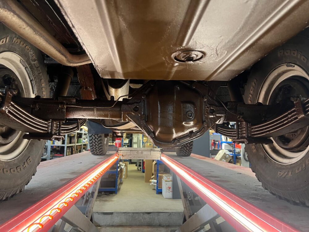 Underside view of vehicle on lift showing axle and wheels