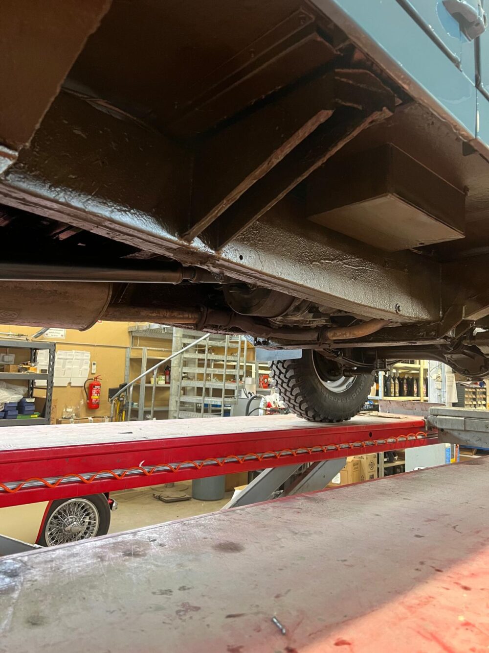 Underside view of a vehicle on a red hydraulic lift