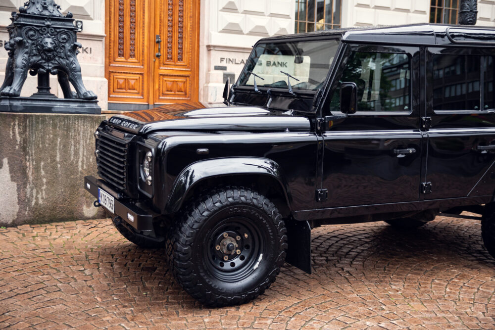 Black Land Rover Defender parked on cobblestone street