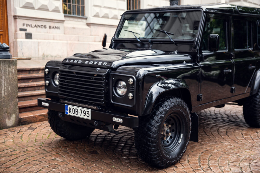 Black Land Rover Defender parked by stone pavement