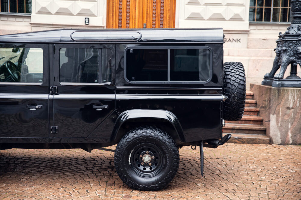 Black SUV parked on cobblestone street near building