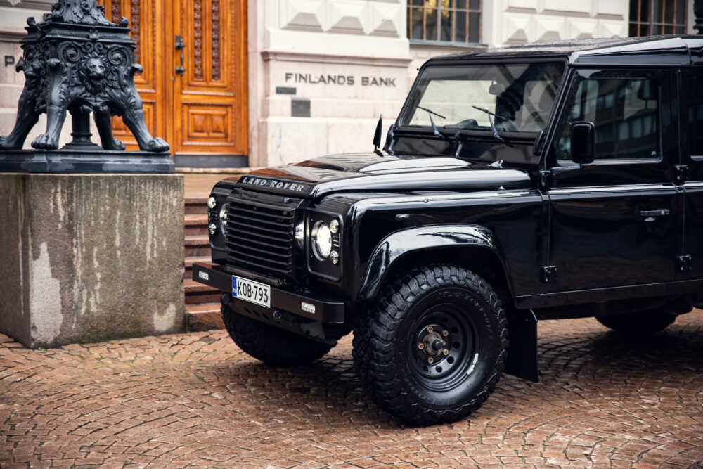 Black Land Rover Defender parked near ornate lion statue