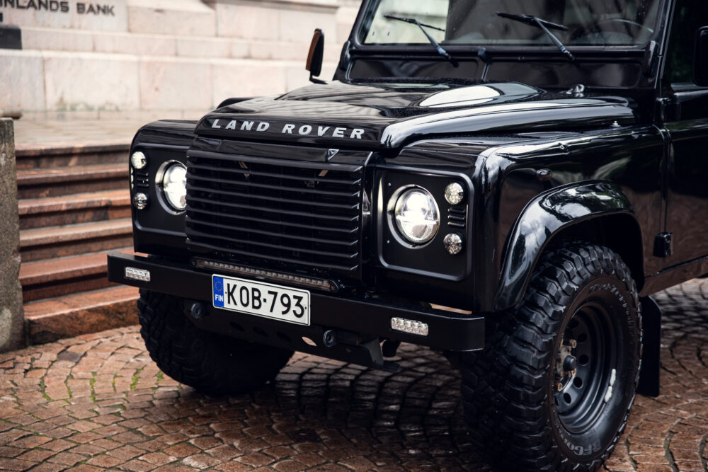 Black Land Rover parked on cobblestone street