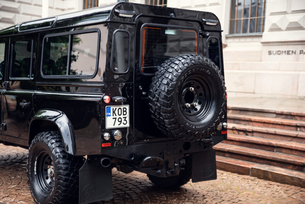 Black off-road SUV with spare wheel parked in city.