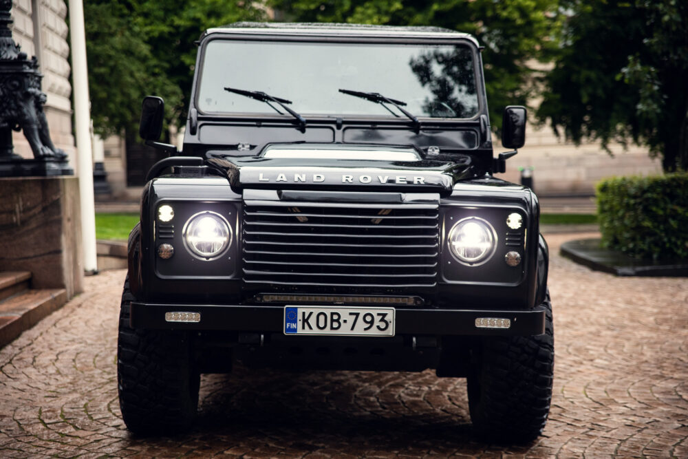 Black Land Rover Defender parked on cobblestone street