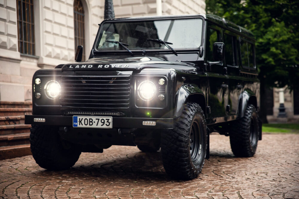 Black Land Rover Defender parked on cobblestone street