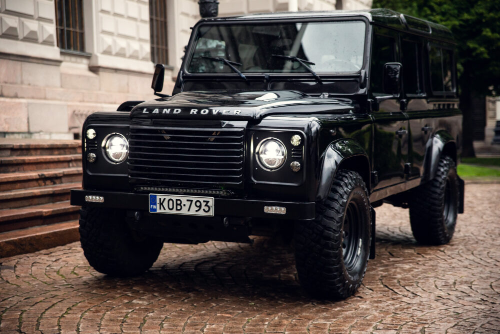 Black Land Rover Defender parked on cobblestone road