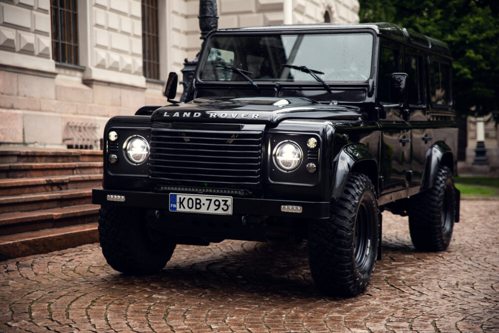 Black Land Rover Defender parked on cobblestone street