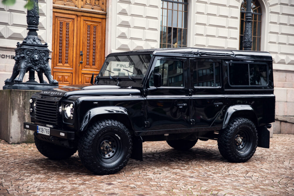 Black Land Rover Defender parked on cobblestone street