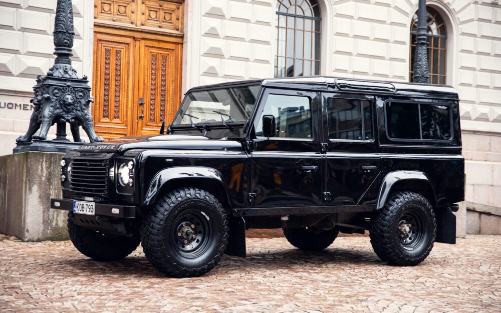 Black Land Rover Defender parked on cobblestone street
