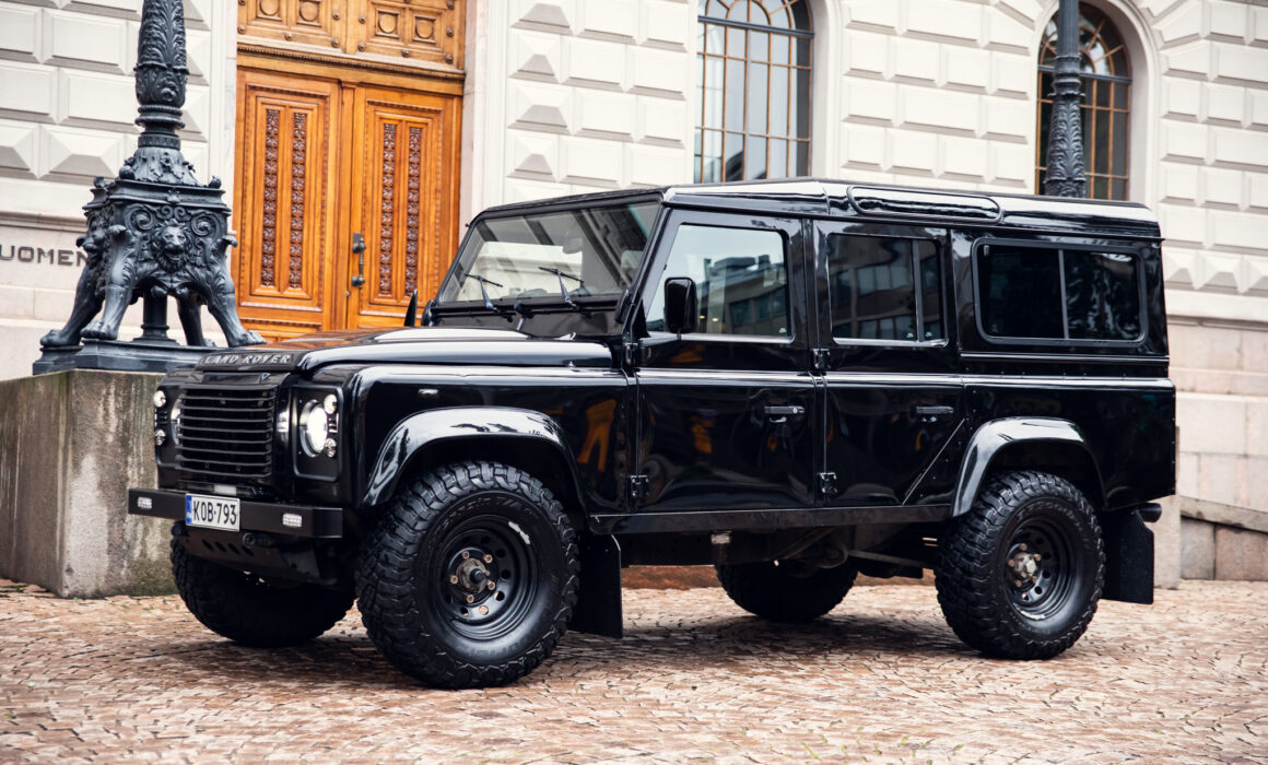 Black Land Rover Defender parked on cobblestone street
