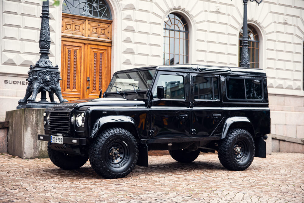 Black Land Rover Defender parked near historic building
