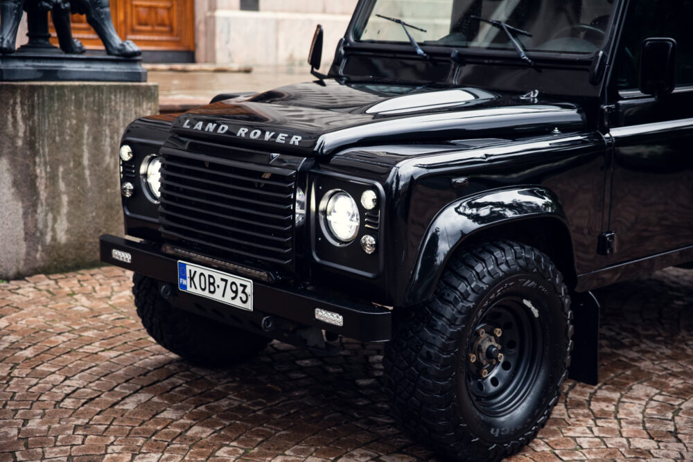 Black Land Rover Defender on cobblestone street