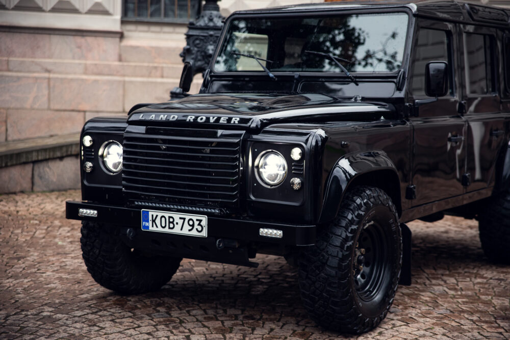 Black Land Rover Defender parked on cobblestone street