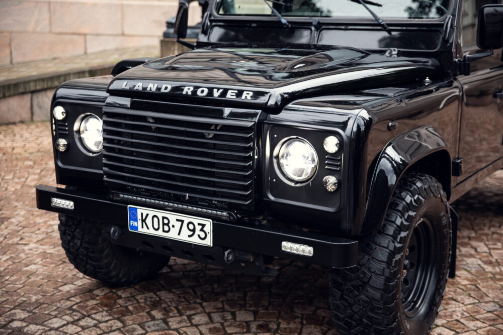 Black Land Rover Defender parked on cobblestone street