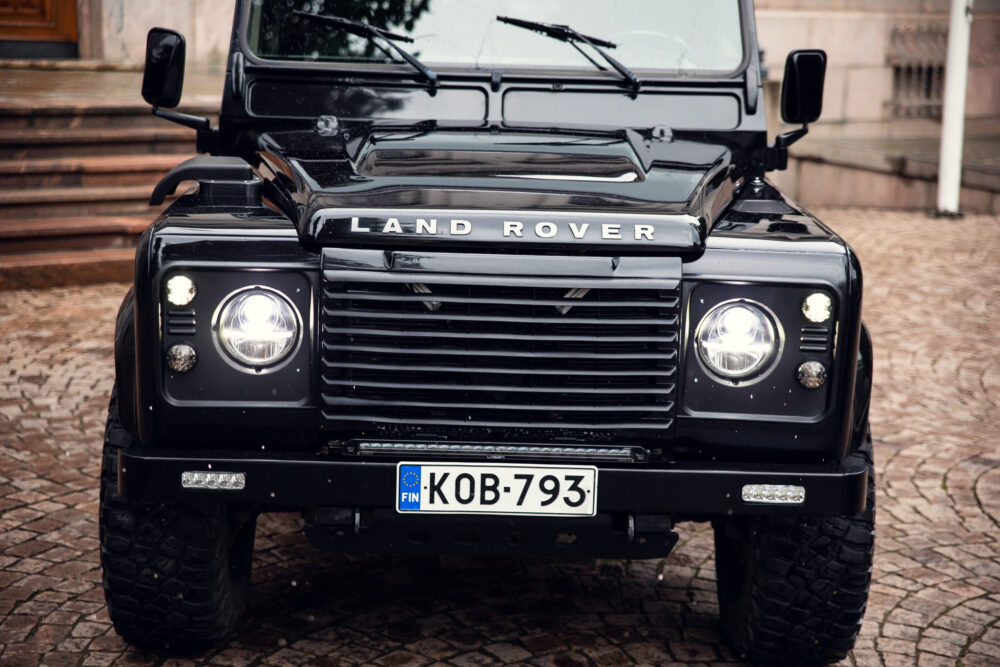 Black Land Rover Defender parked on cobblestone
