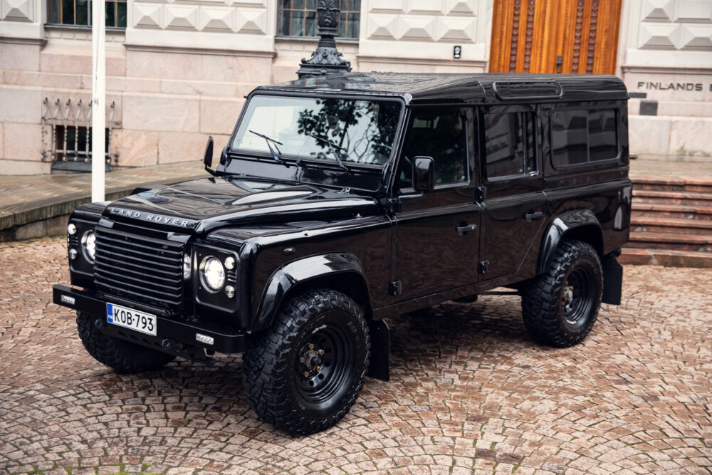Black Land Rover Defender parked on cobblestone street
