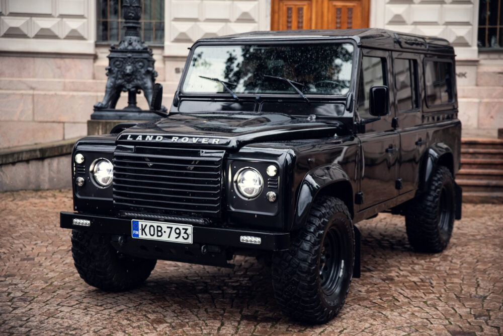 Black Land Rover Defender parked near historic building
