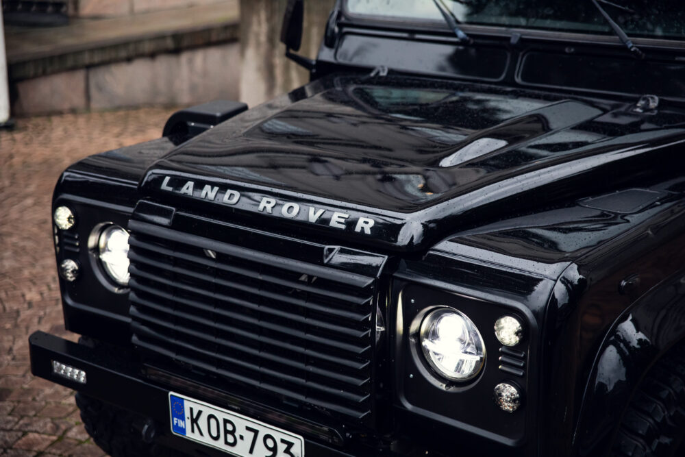 Black Land Rover with European license plate, wet