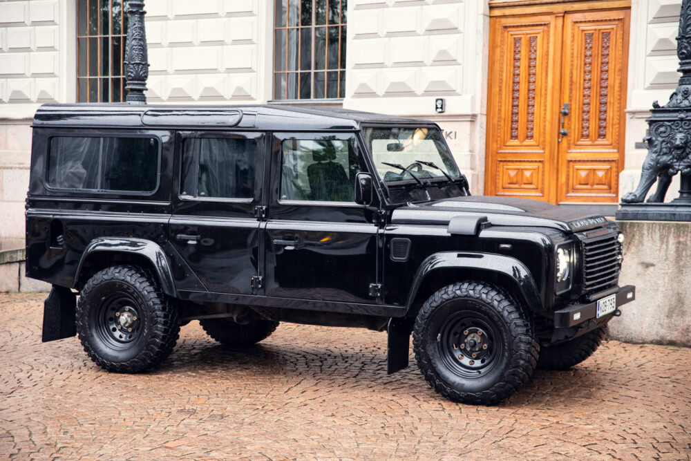 Black Land Rover Defender parked on cobblestone street