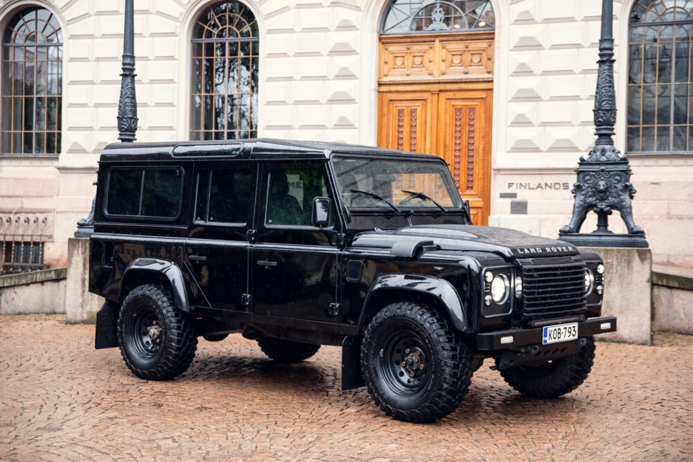 Black Land Rover parked near historical building