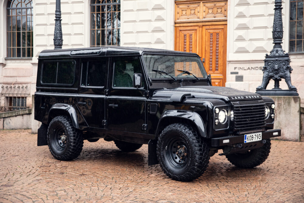 Black Land Rover Defender parked near historic building