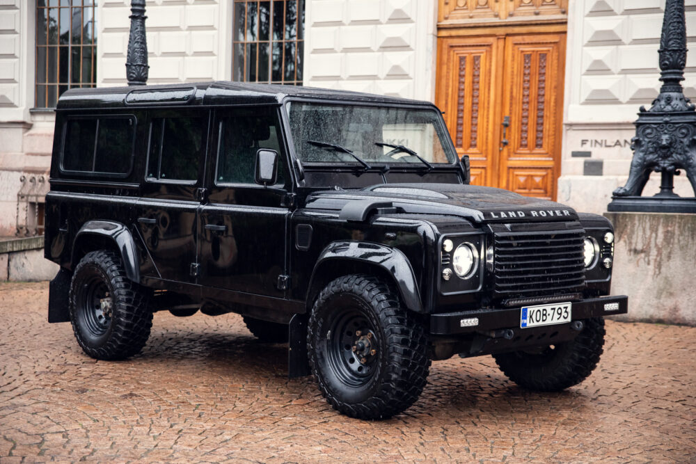 Black Land Rover parked on cobblestone street