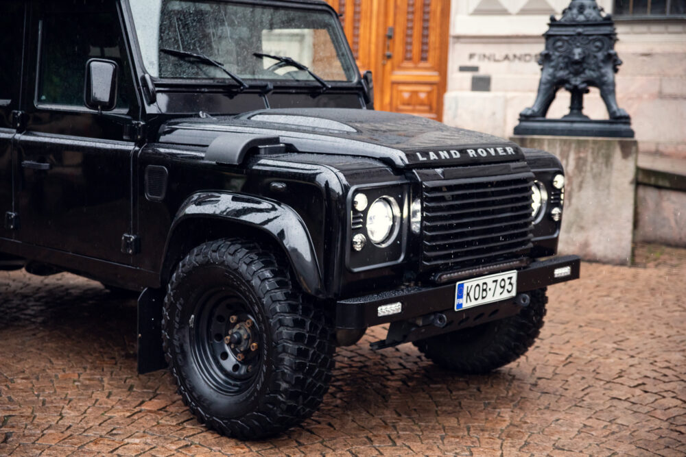 Black Land Rover parked on cobblestone street