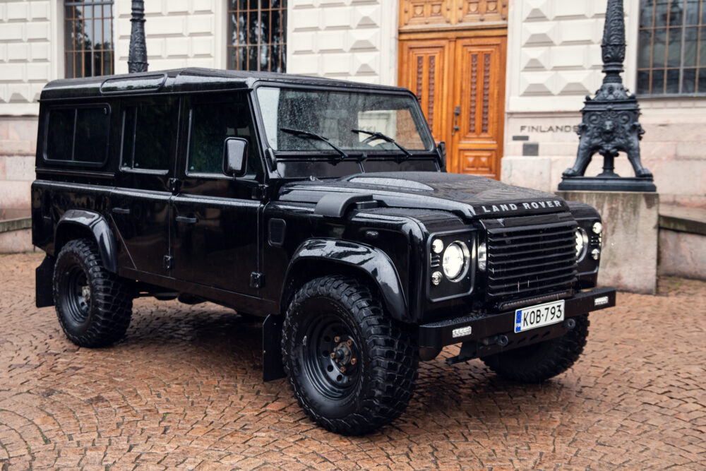 Black Land Rover Defender parked on cobblestone street