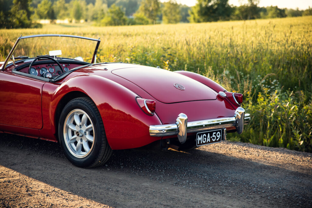 Red vintage convertible car on country road at sunset