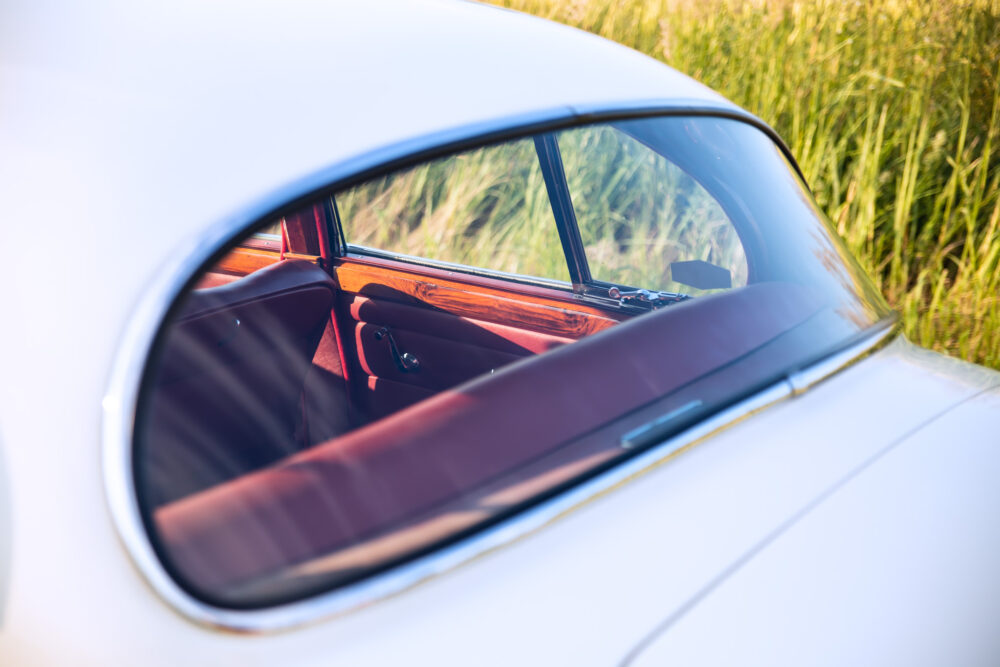 Vintage car interior through window, lush field background