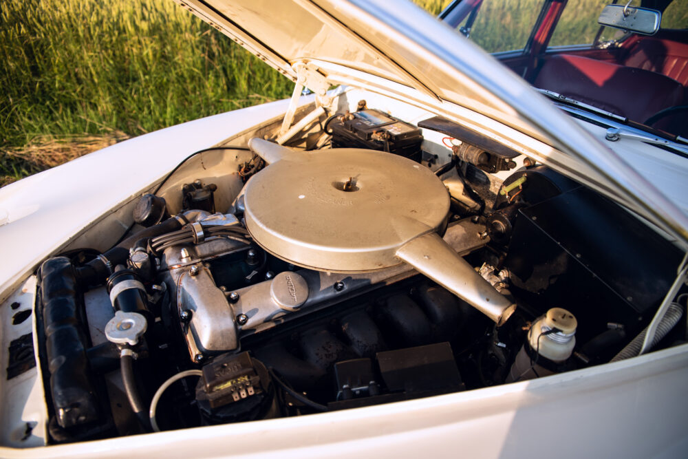 Vintage car engine compartment open in a field