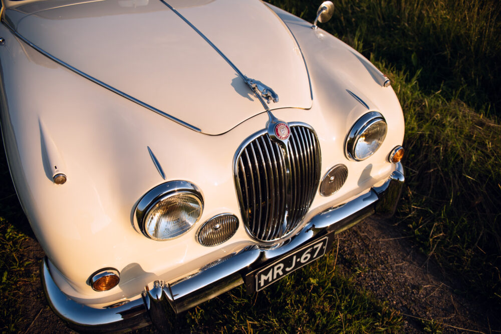 Vintage white Jaguar car on grass at sunset