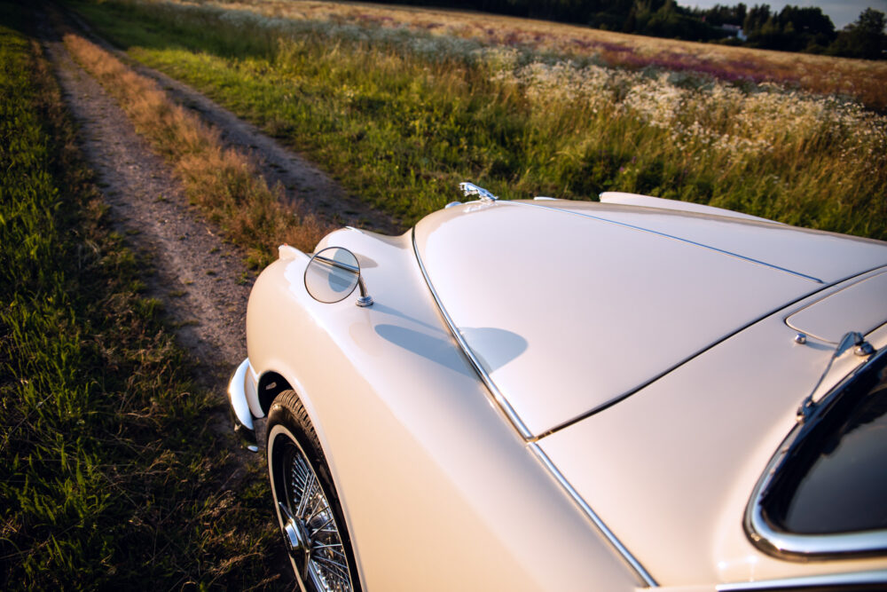 Vintage white car on countryside dirt road at sunset