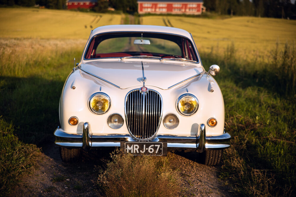Vintage white Jaguar car in rural setting at sunset