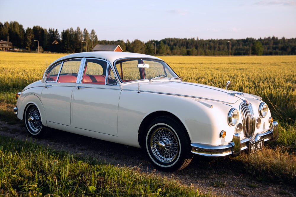 Vintage white Jaguar car in countryside field