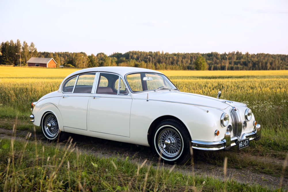 Vintage white Jaguar car in countryside field