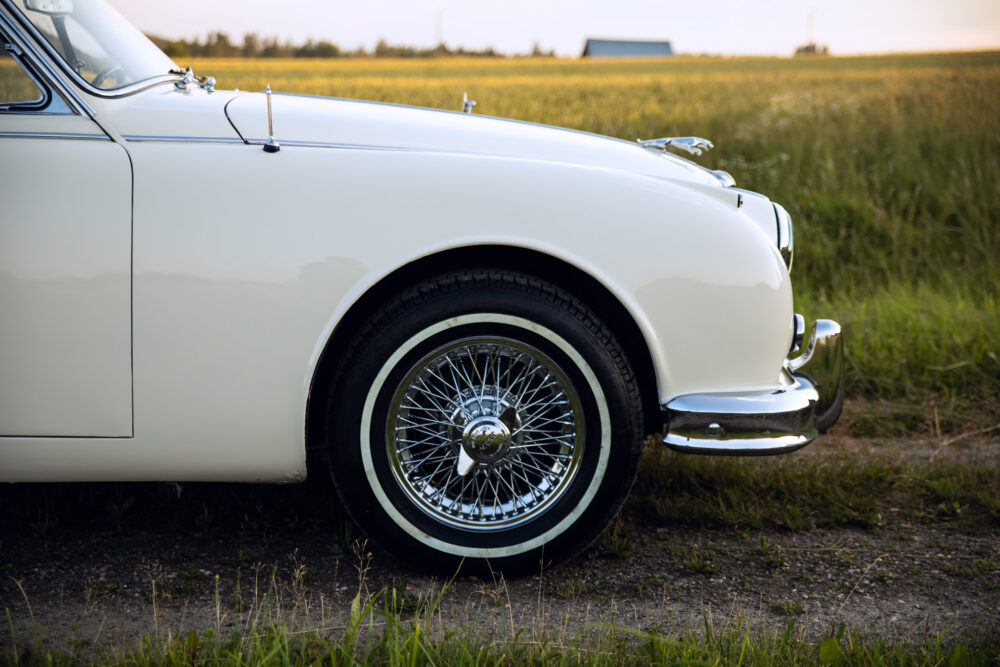 Vintage white car in a field at sunset