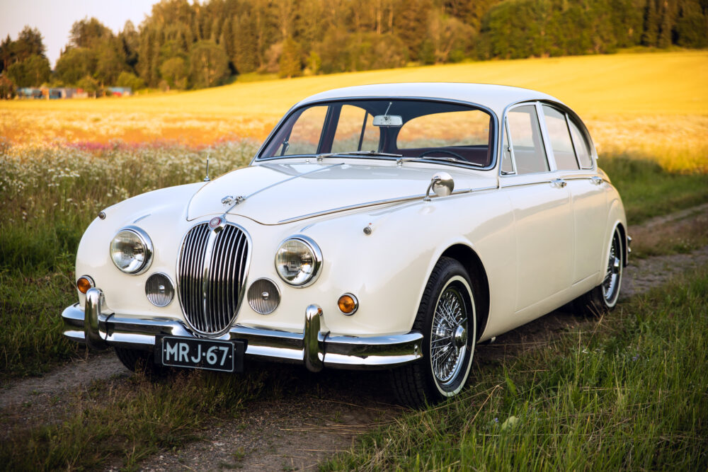 Vintage white Jaguar car parked in a field