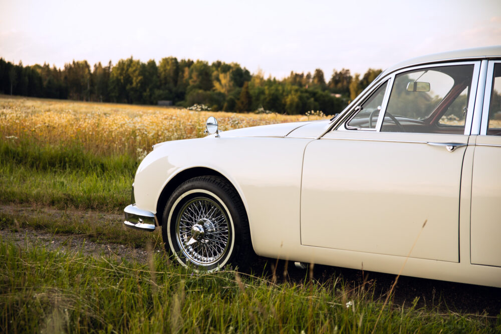 Vintage white car in rural field at sunset