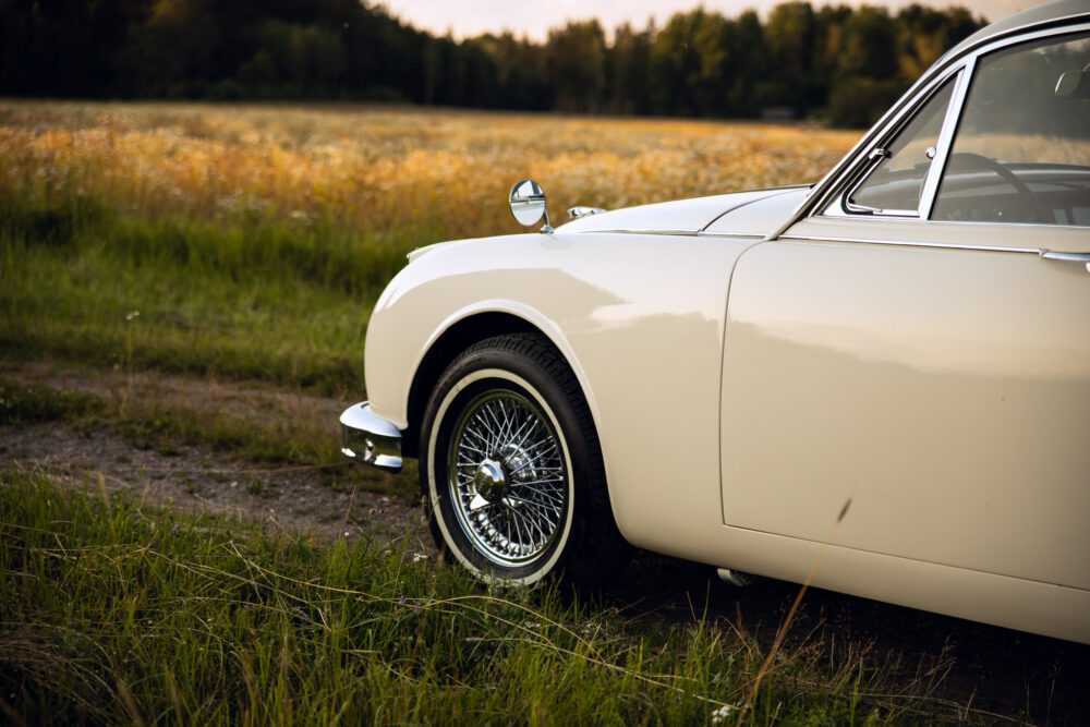 Classic white car parked in a field at sunset