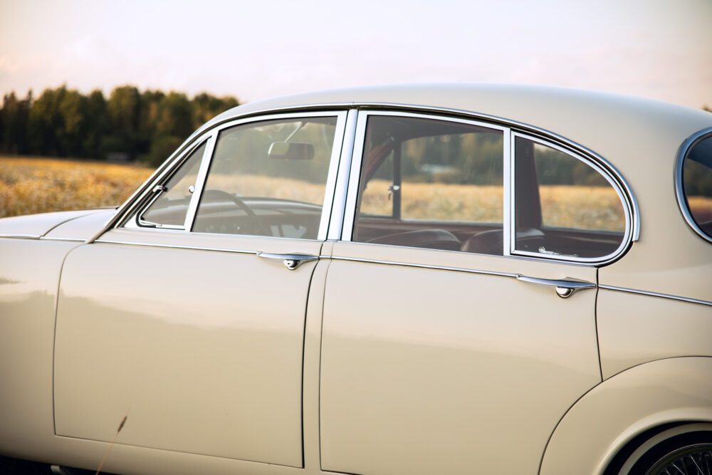 Vintage cream car parked in golden field at sunset