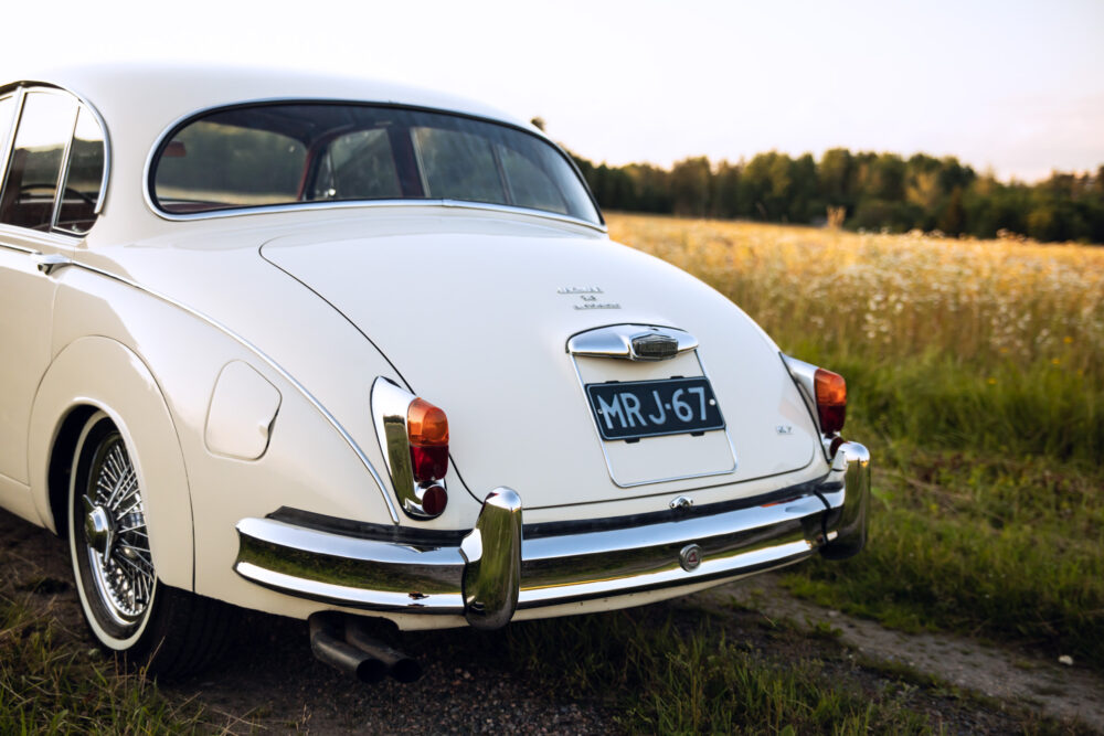 Vintage white car parked by a field at sunset