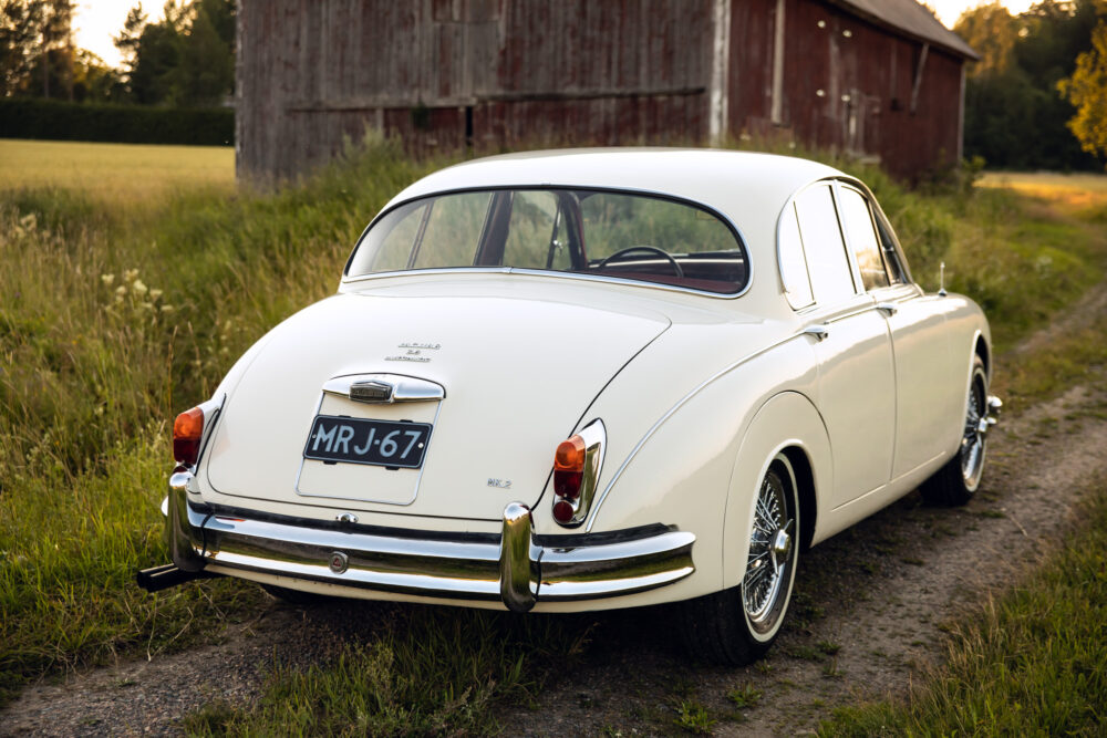 Vintage white Jaguar Mark 2 car near rustic barn