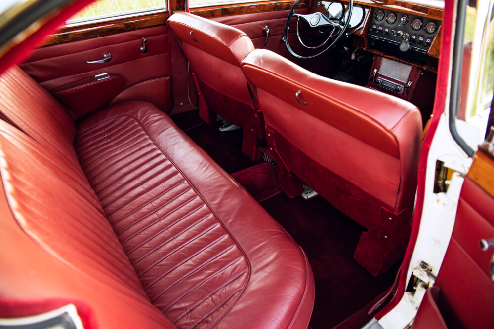 Vintage red car interior with leather seats and dashboard.