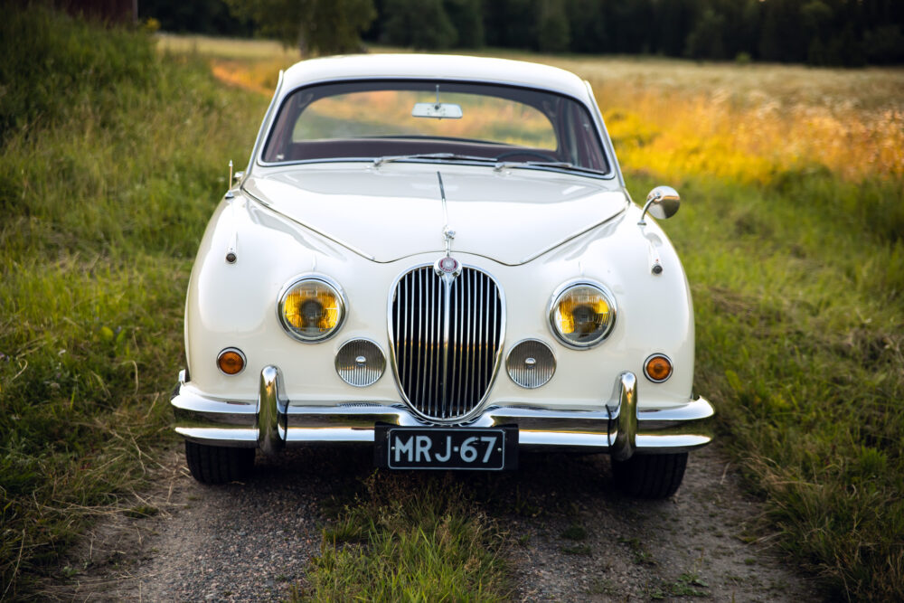 Vintage white Jaguar car parked in a grassy field