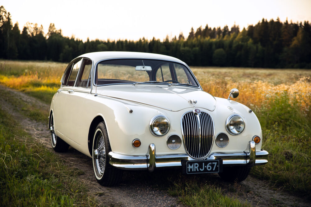 Vintage white Jaguar car in rural sunset landscape